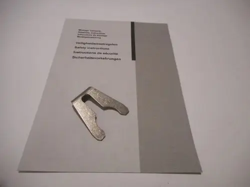 Metallic clip auf einer Anleitung, die Sicherheitshinweise und Montageanleitungen von Remeha enthält. Der Clip ist zur Befestigung von Komponenten gedacht.